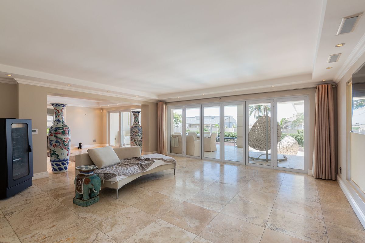 Spacious living area featuring polished travertine flooring, recessed ceiling lighting, and large bi-fold glass doors providing seamless access to the outdoor patio.