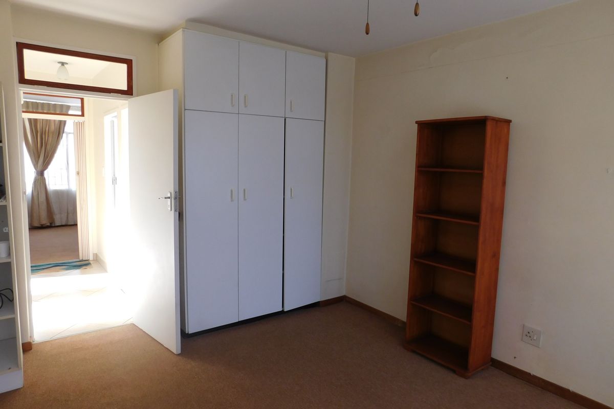 A bedroom featuring built-in cupboards, carpeted flooring, and a ceiling fan, offering a functional space ready for personalization.