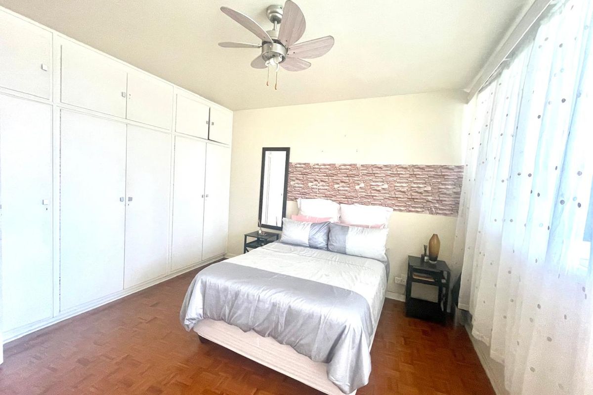 A bedroom featuring parquet flooring, a ceiling fan, and extensive built-in cupboard storage.