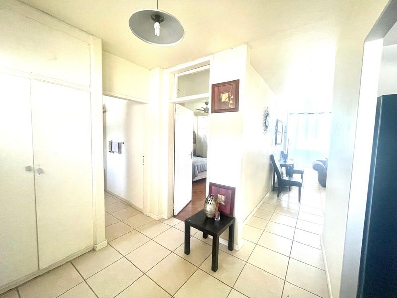 A functional hallway featuring tiled flooring and built-in storage cupboards, providing access to adjacent rooms within the apartment.