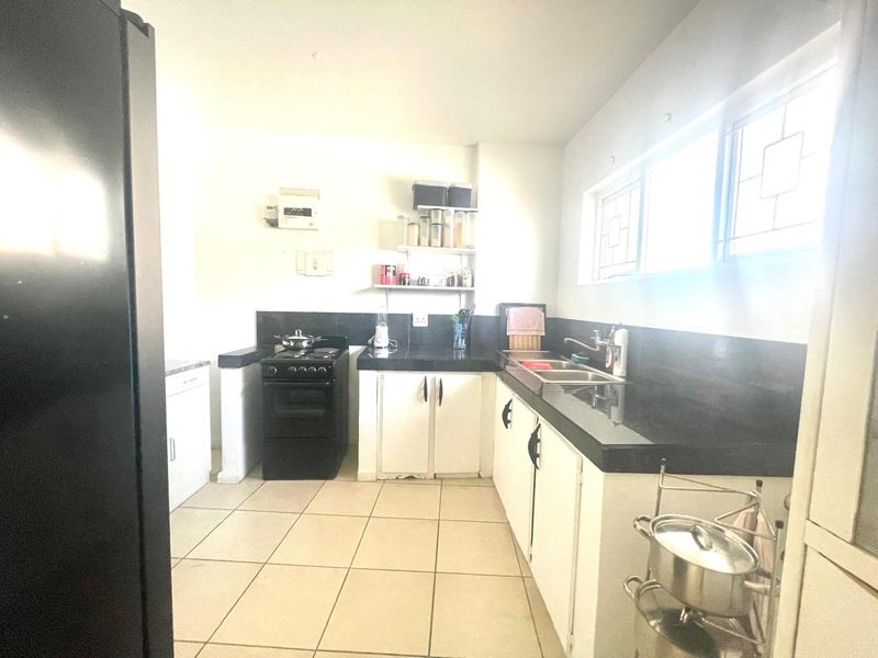Functional kitchen featuring black granite countertops, white cabinetry, a freestanding stove, and double basin sink with tiled flooring.