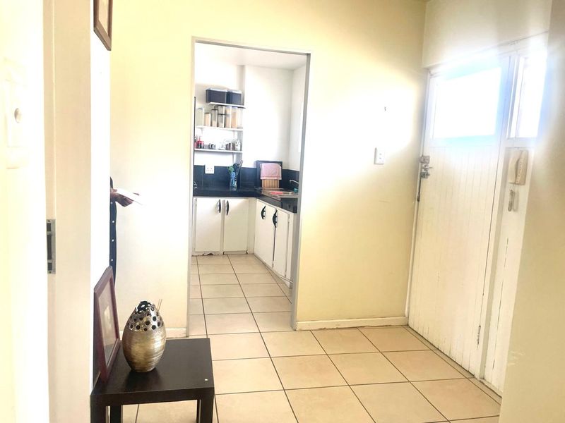 Entryway leading into a functional kitchen area with tiled flooring and built-in cabinetry.