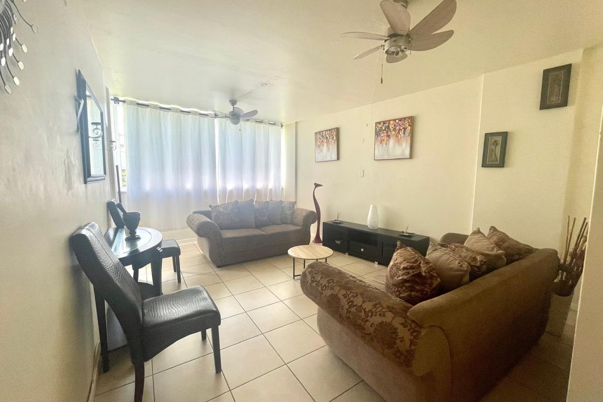A living room featuring tiled flooring and ceiling fans, providing a functional and comfortable space for relaxation.