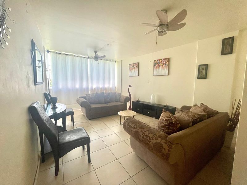 A living room featuring tiled flooring and ceiling fans, providing a functional and comfortable space for relaxation.