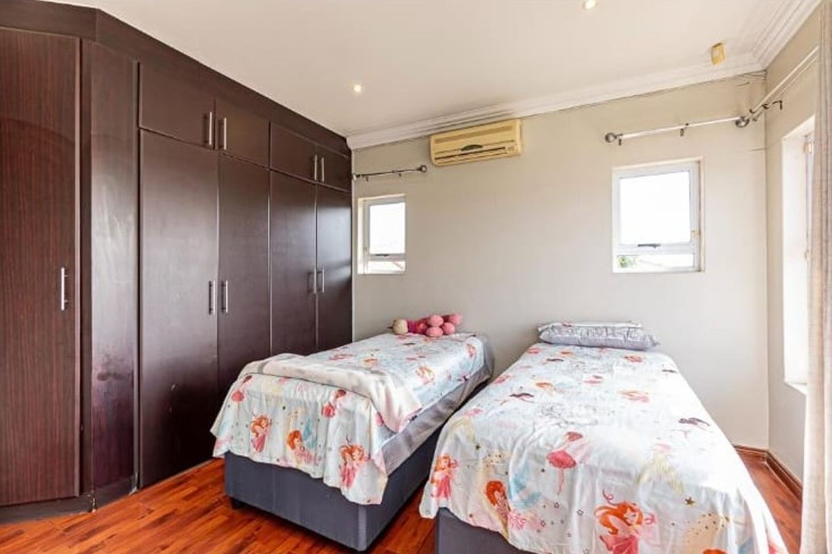 A well-maintained bedroom featuring extensive dark wood built-in cabinetry, timber flooring, and a wall-mounted air conditioning unit.