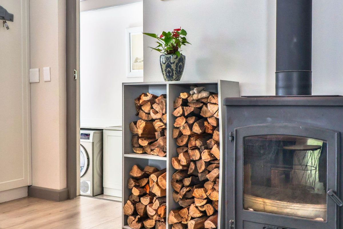 A cozy living area featuring a modern wood-burning fireplace and light-toned laminate flooring, with a view through to an adjacent utility space.
