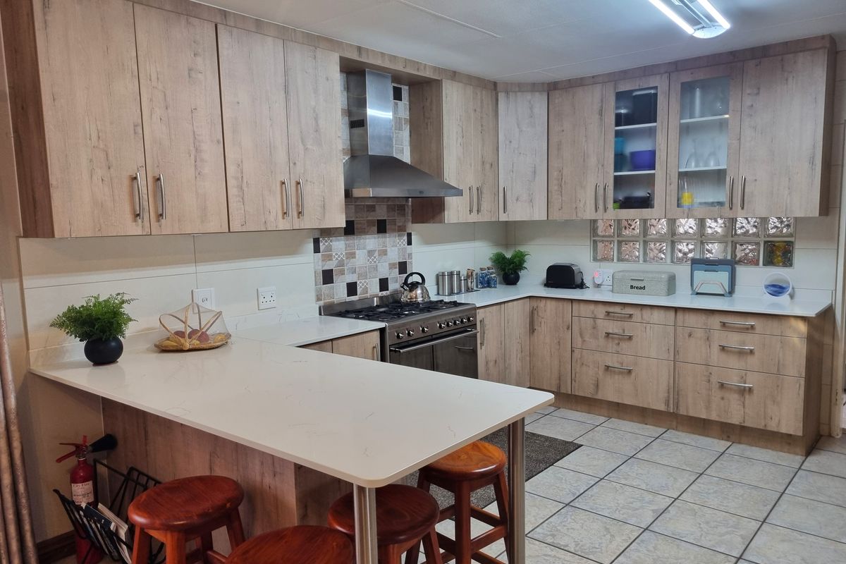Modern kitchen featuring wood-look cabinetry, quartz countertops, a breakfast bar, and a stainless steel gas stove with an extractor fan.