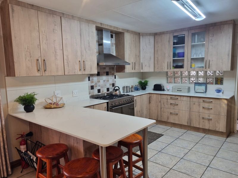 Modern kitchen featuring wood-look cabinetry, quartz countertops, a breakfast bar, and a stainless steel gas stove with an extractor fan.
