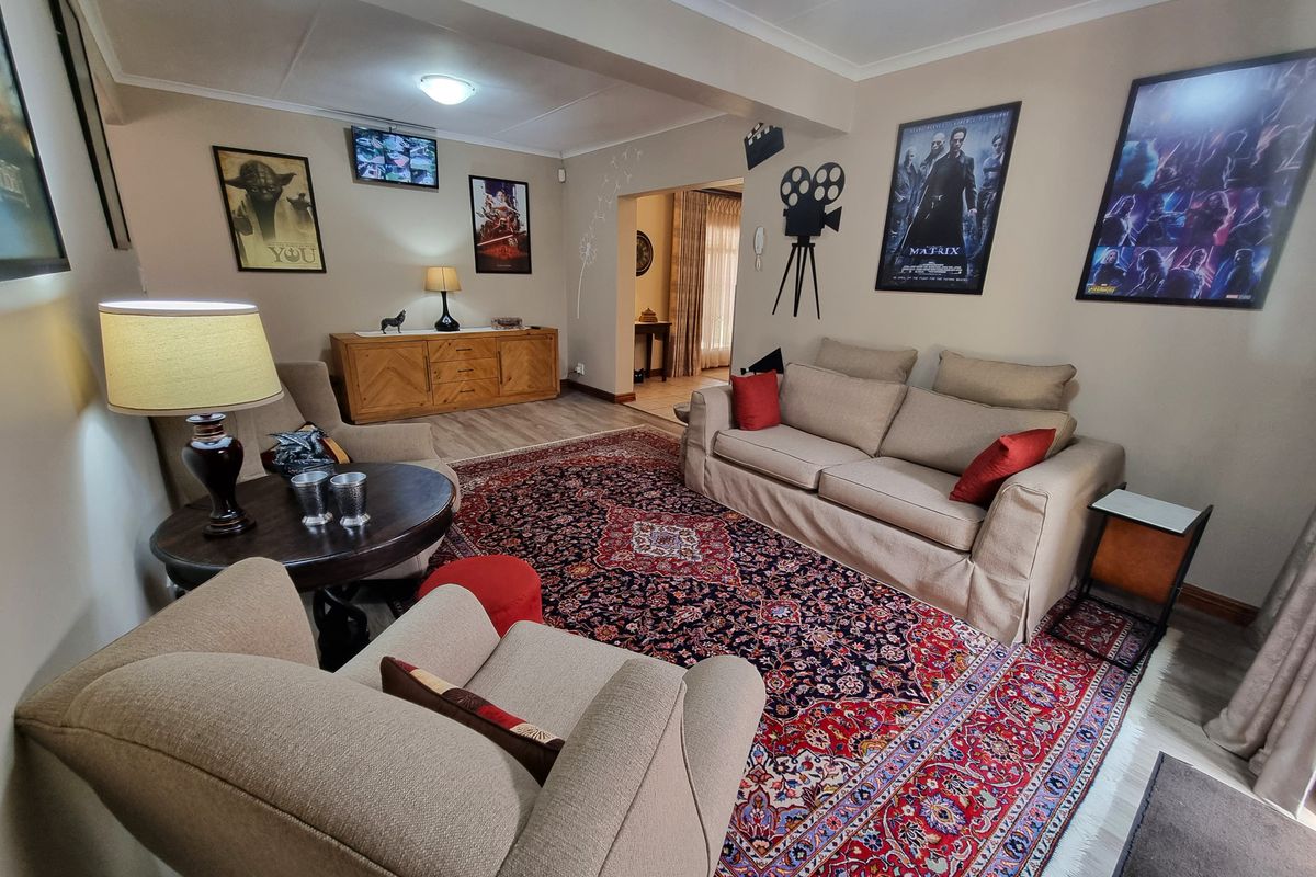 A comfortable living room featuring laminate flooring and cove cornice, with an open transition to an adjacent room.