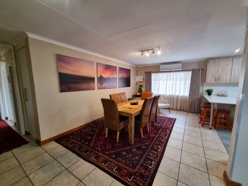 Open-plan living and dining area featuring tiled flooring, a split-system air conditioner, and a functional kitchen with island seating.