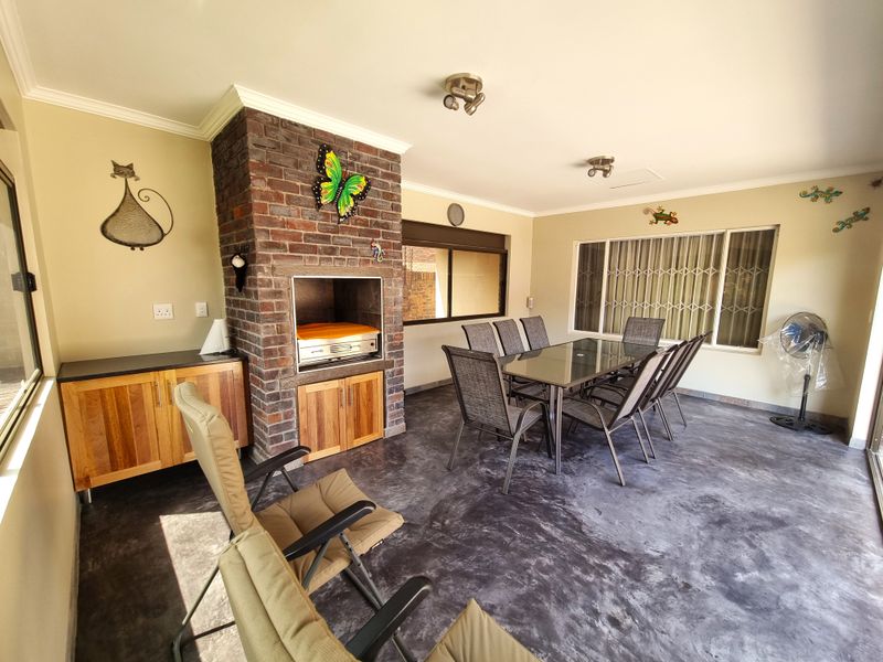 Covered patio area featuring a built-in brick braai, custom cabinetry, and durable flooring, ideal for outdoor dining and entertainment.