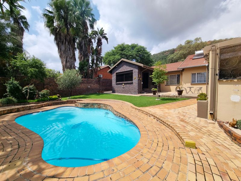 A well-maintained outdoor area featuring a swimming pool, brick paving, and a landscaped garden with a brick boundary wall.