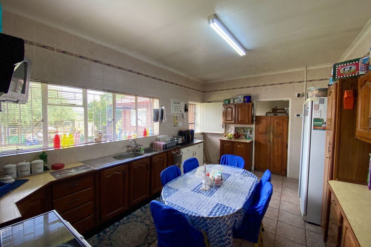 A functional kitchen featuring wooden cabinetry, tiled backsplash, and tiled flooring, offering a traditional layout with ample space for a dining area.