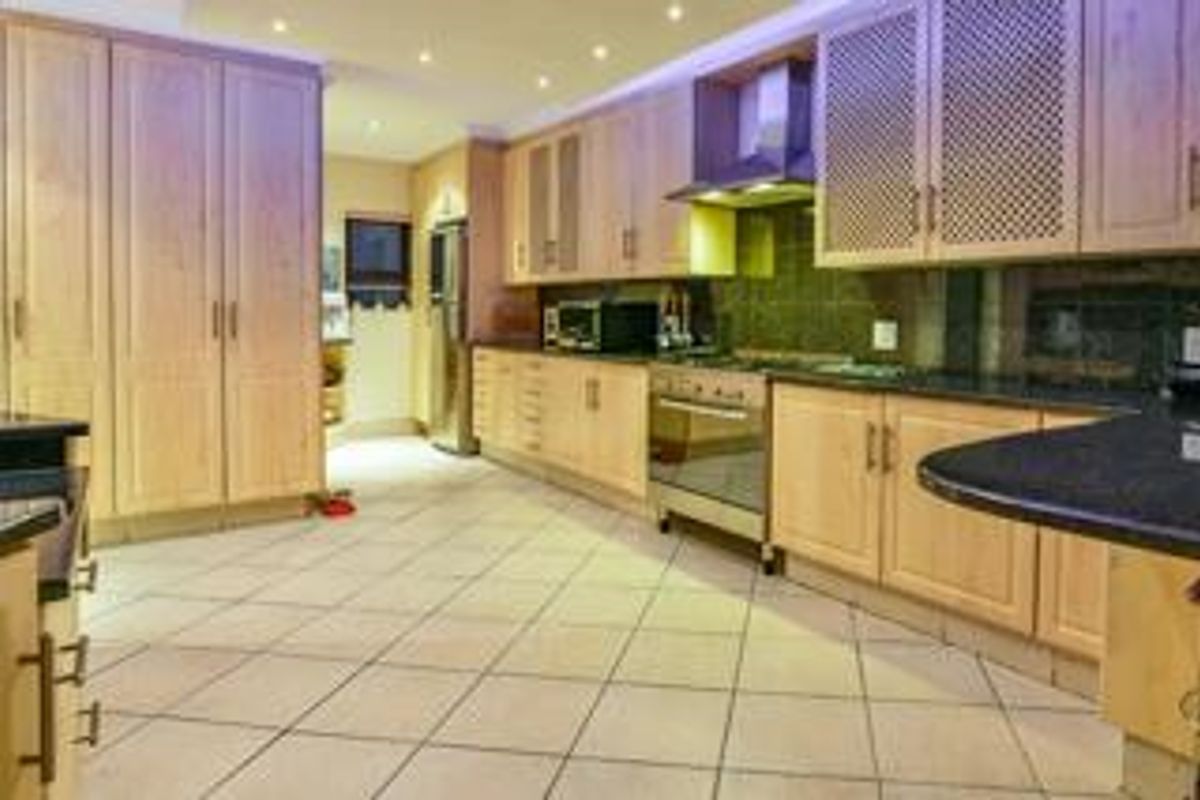 Spacious kitchen featuring light wood cabinetry, dark granite countertops, built-in oven, extractor fan, and tiled flooring with recessed ceiling lighting.