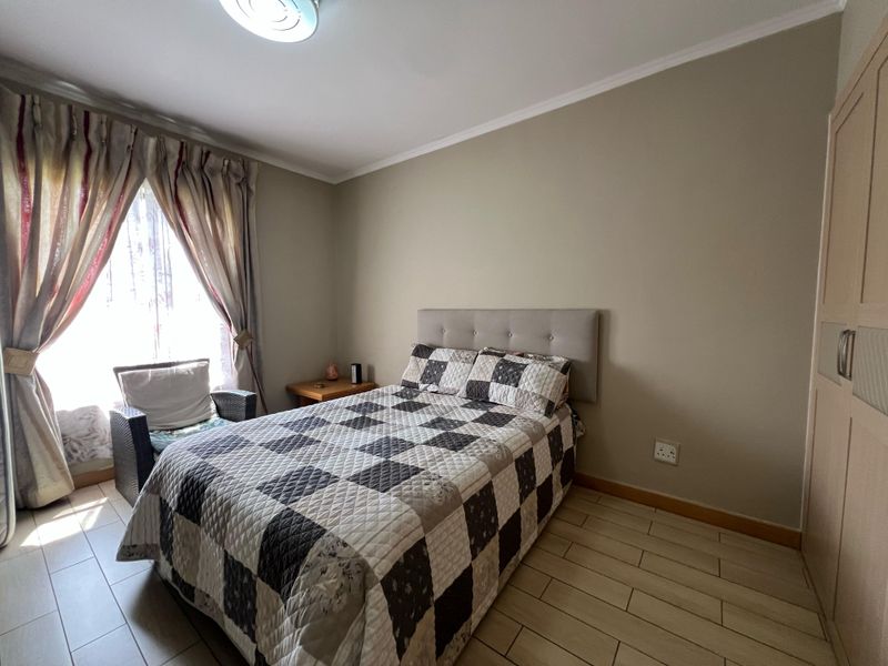 A well-maintained bedroom featuring tiled flooring, neutral wall tones, and a built-in wardrobe, offering a comfortable and functional living space.