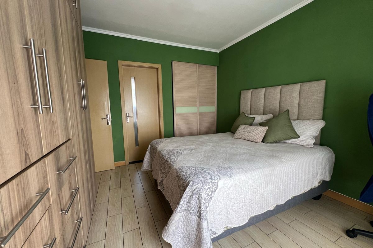 A well-maintained bedroom featuring wood-look laminate flooring, extensive built-in cabinetry, and a bold green accent wall.