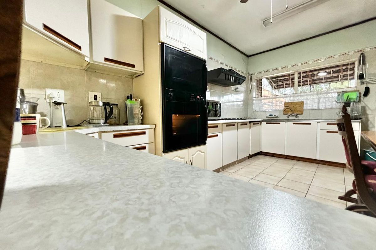 A functional kitchen featuring white built-in cabinetry, laminate countertops, a built-in oven, and tiled flooring, offering a classic layout with potential for modernization.