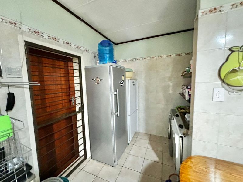 A functional scullery or utility area featuring tiled walls and flooring, providing additional storage and workspace adjacent to the main kitchen area.