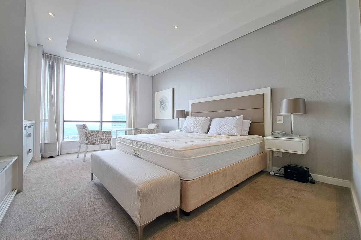 Spacious bedroom featuring floor-to-ceiling windows with natural light, recessed ceiling lighting, and neutral wall-to-wall carpeting.