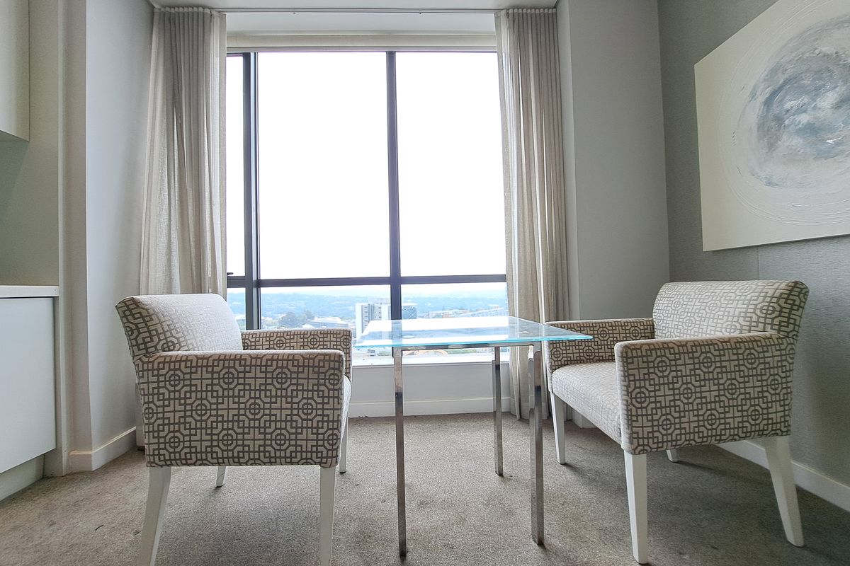 A bright living area featuring large floor-to-ceiling windows with expansive views and neutral wall finishes.