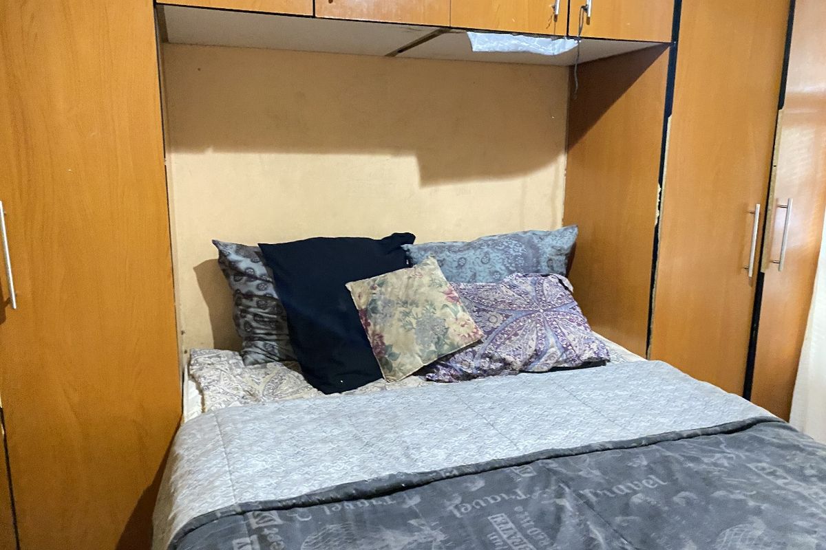 A bedroom featuring built-in wooden cabinetry and overhead storage units surrounding the bed area.