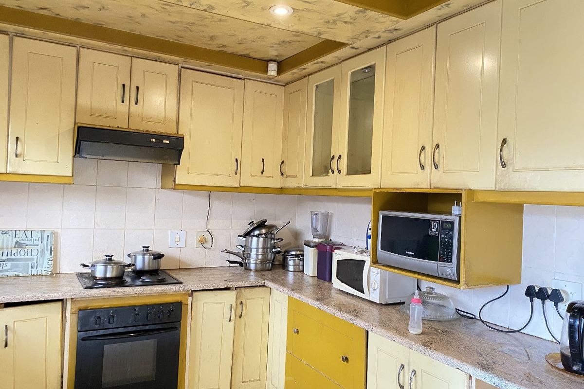 A functional kitchen featuring built-in cabinetry, a fitted oven, hob, and extractor fan with tiled splashbacks and laminate countertops.