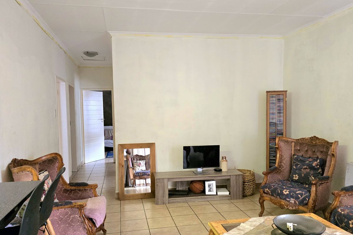 A living room area featuring tiled flooring and neutral walls, requiring cosmetic updates to improve the overall finish and aesthetic appeal.