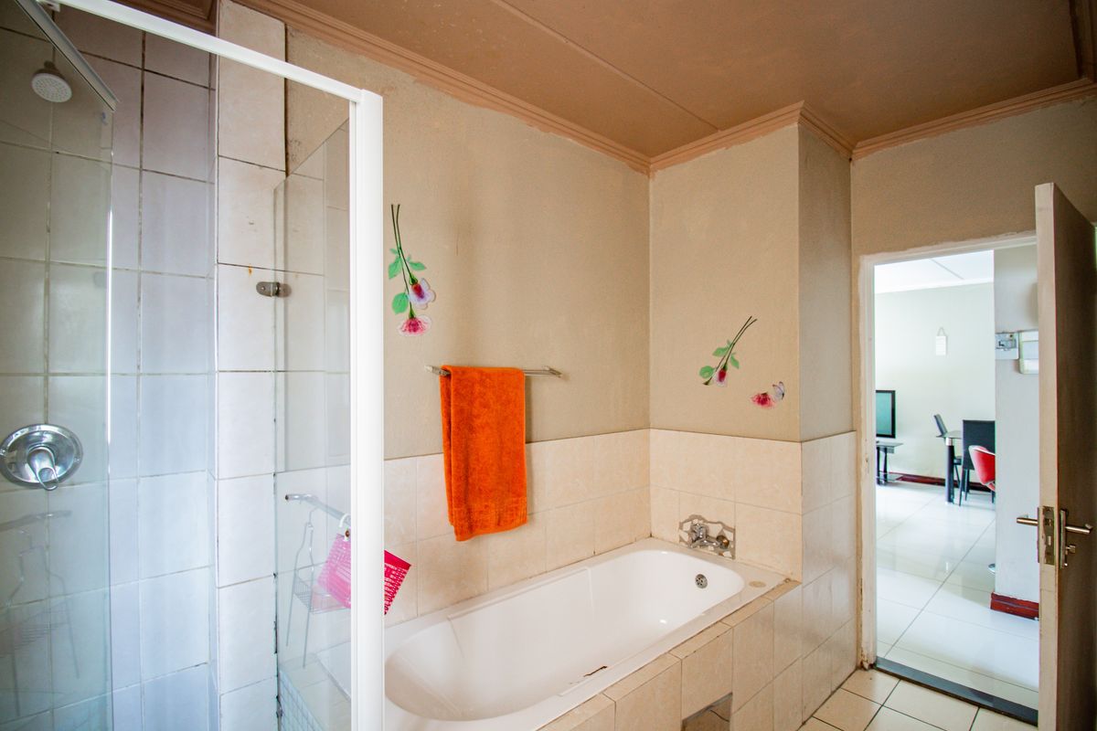 A dated bathroom featuring a built-in bathtub and a separate glass-enclosed shower with tiled finishes.