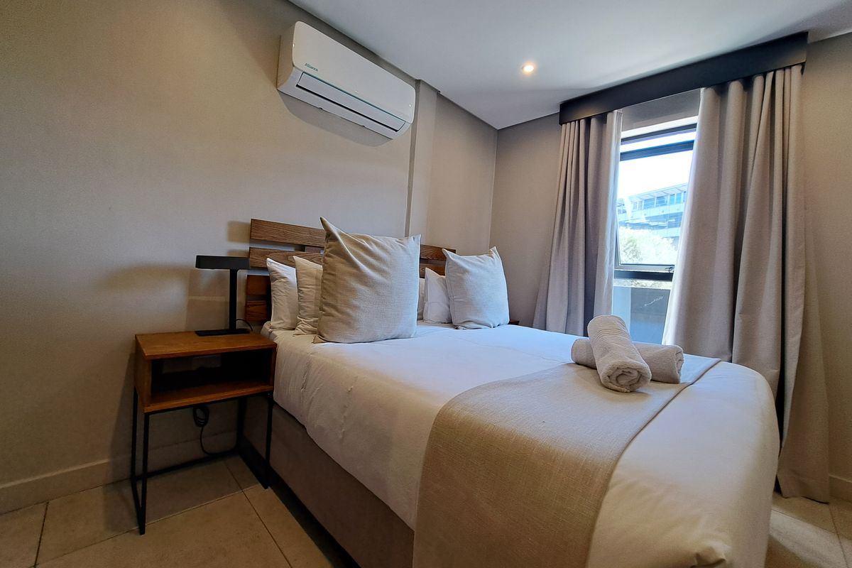 A well-maintained bedroom featuring tiled flooring, recessed lighting, and a wall-mounted air conditioning unit.