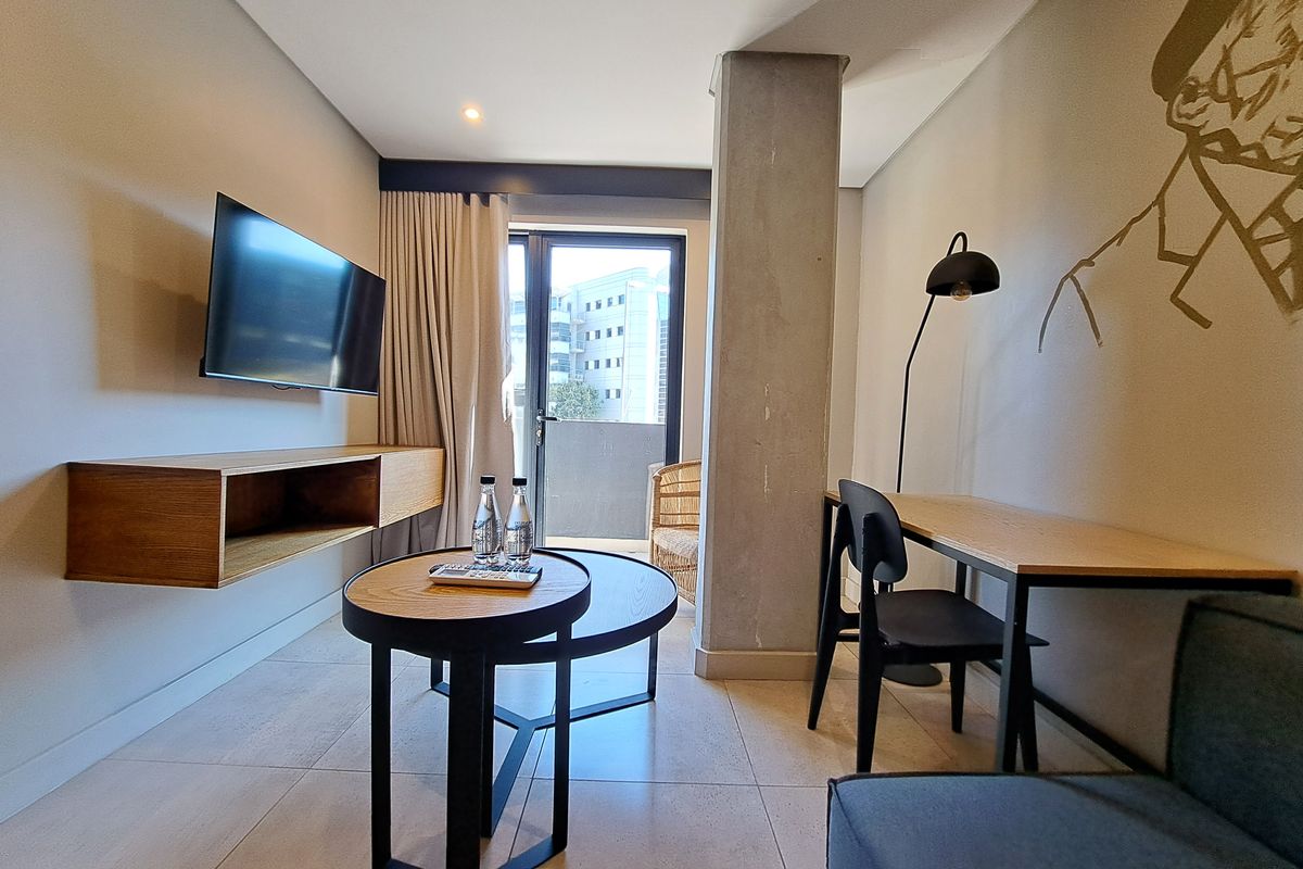 Modern living area featuring tiled flooring, an exposed concrete column, and a floating timber shelf with direct access to a private balcony.