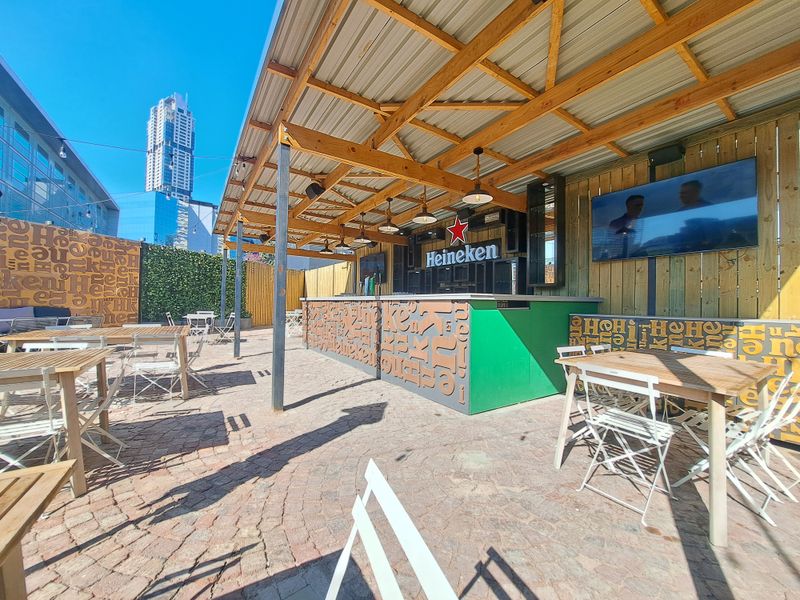 An outdoor bar area featuring a timber-framed roof, paved flooring, and a built-in bar counter, suitable for social gatherings.