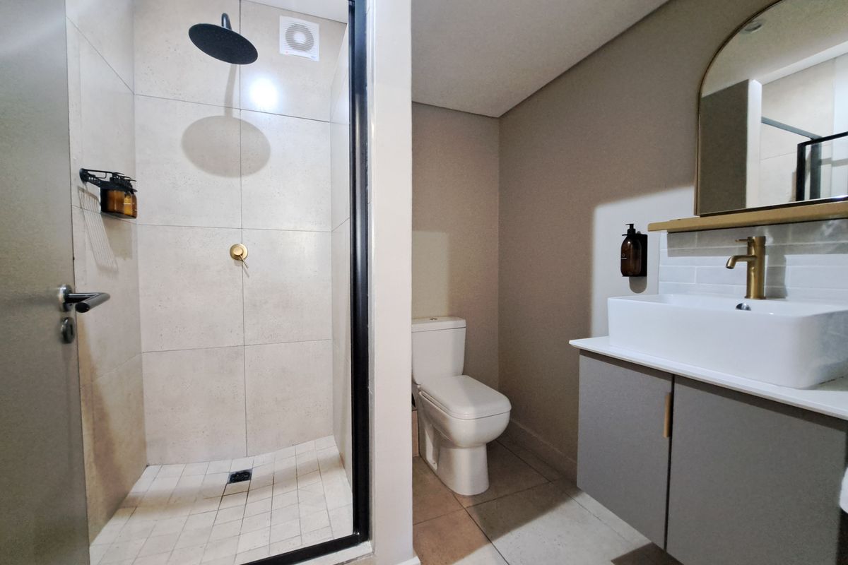 Modern bathroom featuring a walk-in shower with black-framed glass, a contemporary vanity with a vessel sink, and brass fixtures.