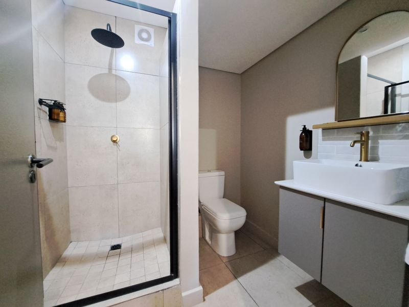 Modern bathroom featuring a walk-in shower with black-framed glass, a contemporary vanity with a vessel sink, and brass fixtures.