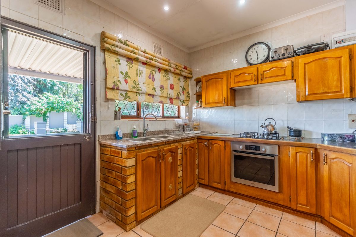 A functional kitchen featuring wooden cabinetry, built-in oven and gas hob, tiled splashbacks, and direct access to the outdoor patio area.