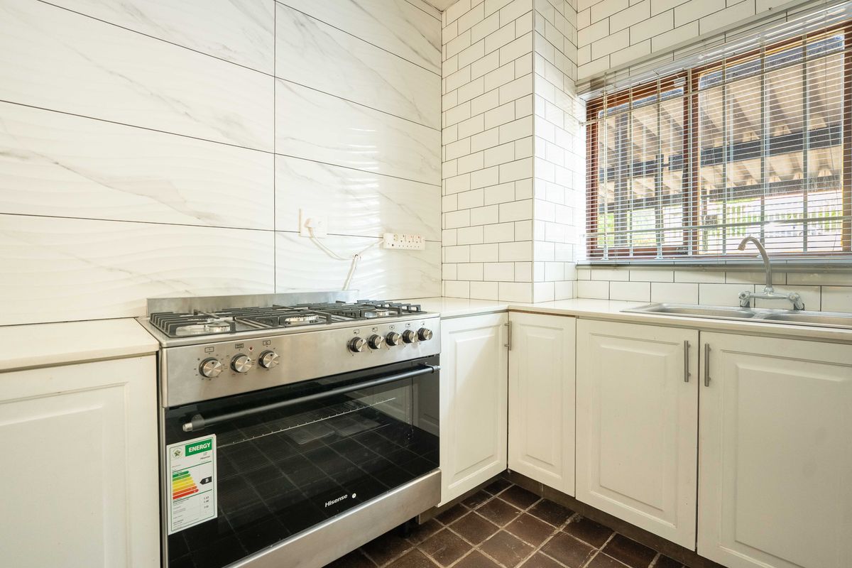 A clean, modern kitchen featuring white cabinetry, subway tile backsplash, marble-effect wall tiles, and a stainless steel gas stove and oven.
