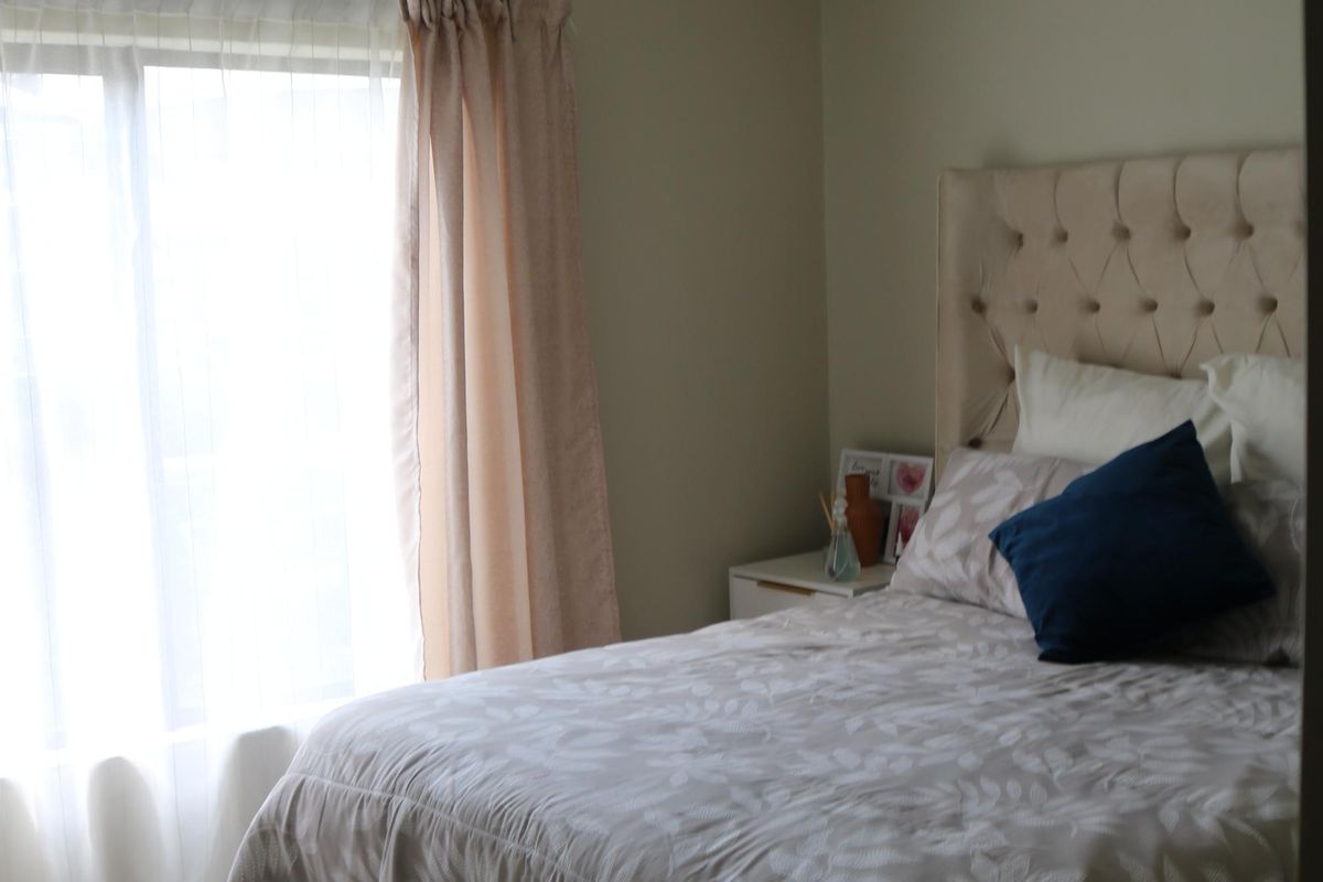 A bedroom featuring neutral wall tones, tiled flooring, and a large window allowing natural light.