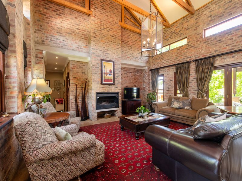 Spacious living room featuring high vaulted ceilings with exposed timber beams, striking brick feature walls, and a built-in fireplace with natural light.