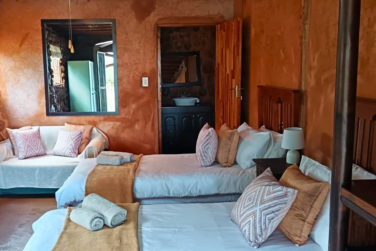 A rustic bedroom featuring textured earth-toned walls, stone accents, and an adjoining bathroom area with a vanity.