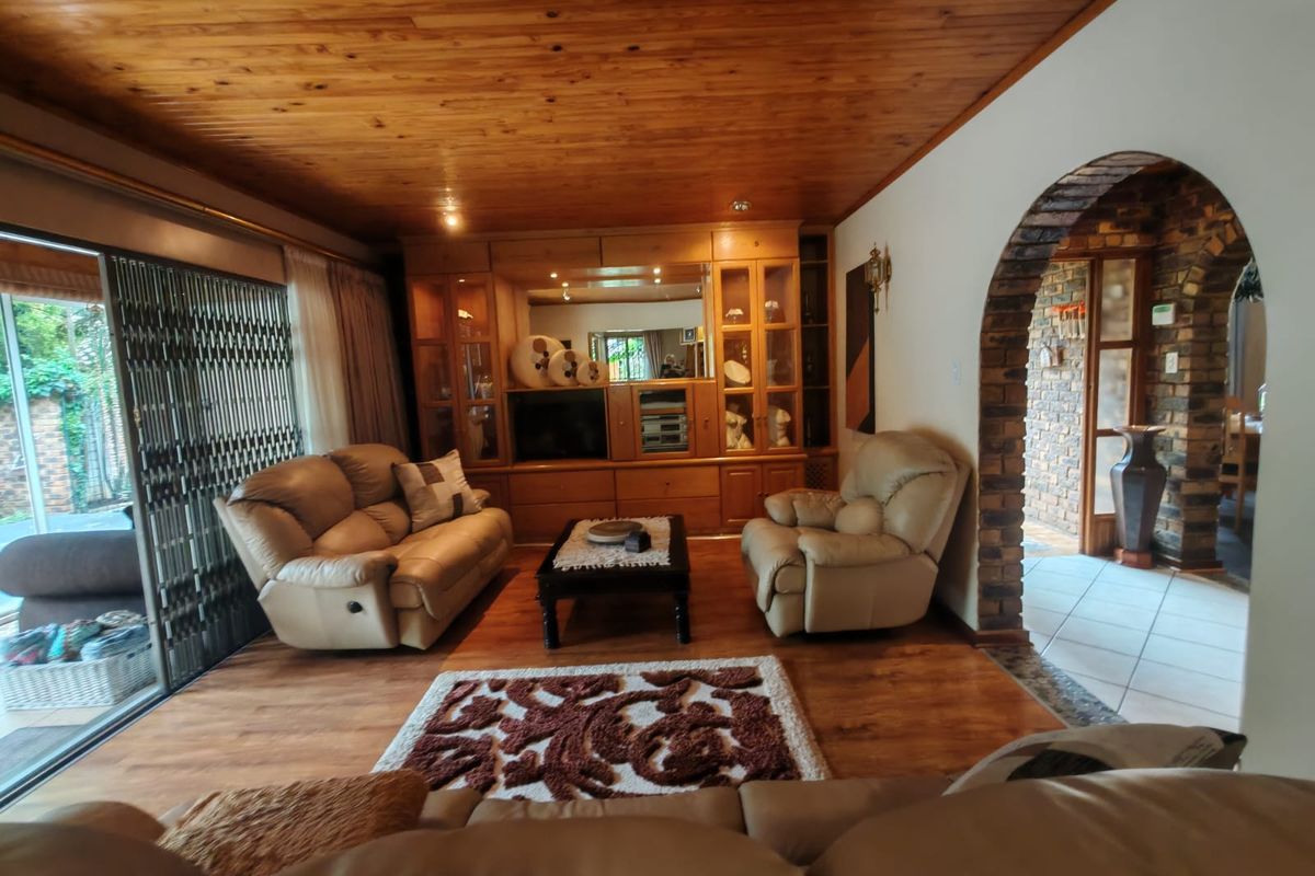 A cozy living room featuring a warm timber ceiling, built-in wooden cabinetry, and a distinctive brick archway leading to an adjacent space.