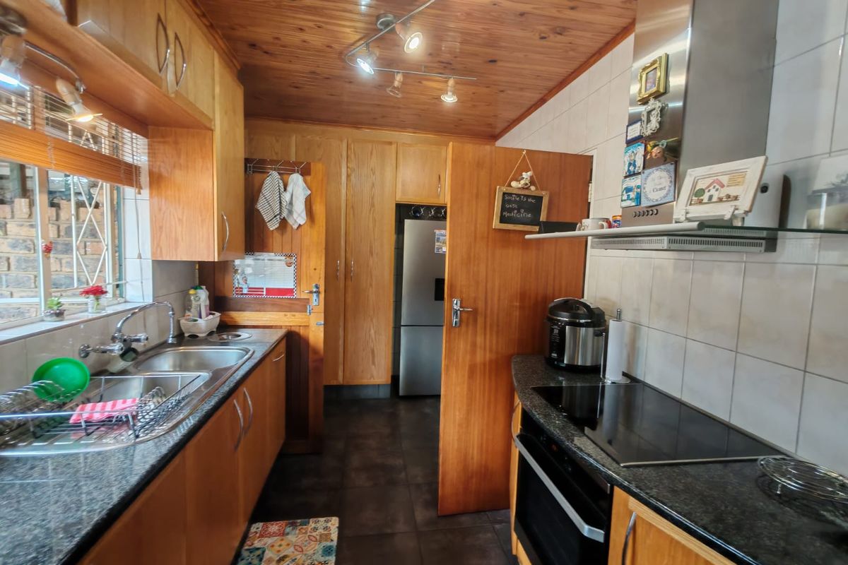 Functional kitchen featuring wooden cabinetry, granite countertops, built-in oven with hob, and a distinctive wooden tongue and groove ceiling.