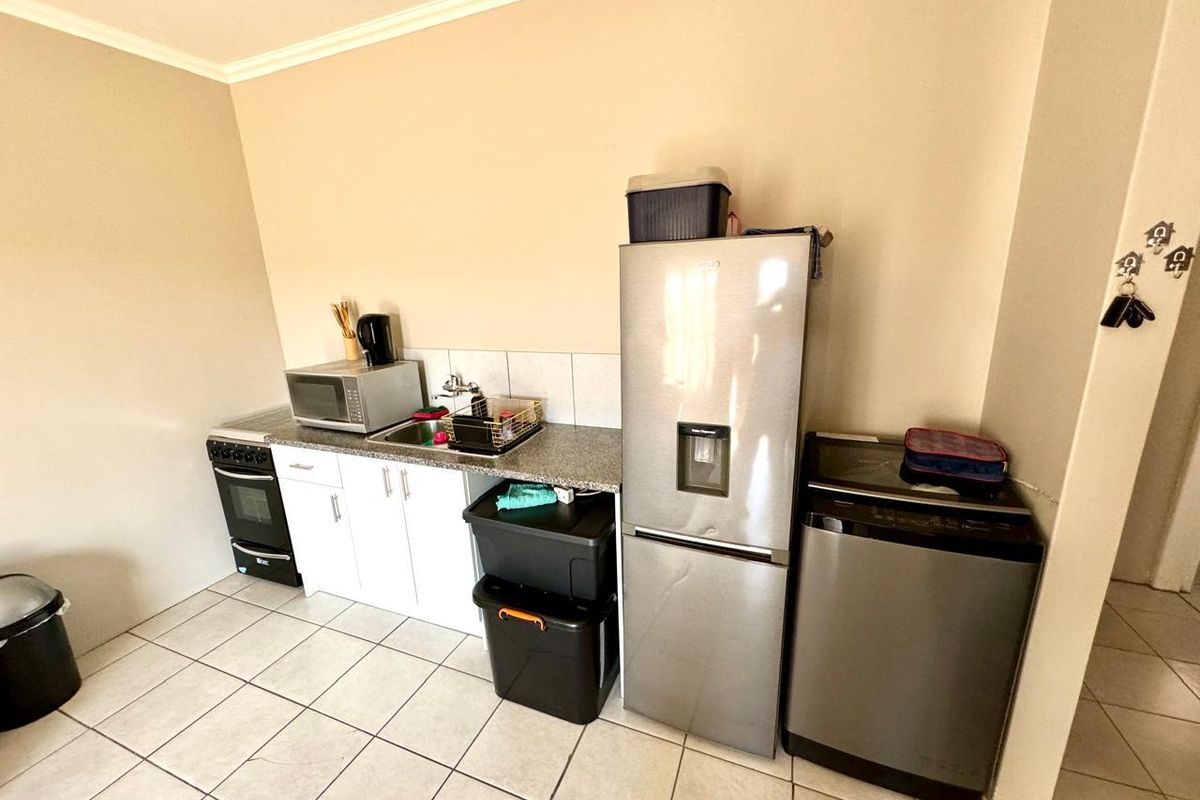 Compact kitchen area featuring tiled flooring, granite countertops, a built-in stove, and a stainless steel sink with tiled splashback.