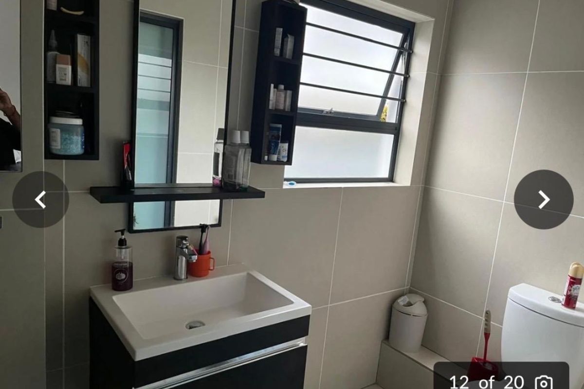 Modern bathroom featuring a wall-mounted vanity with integrated basin, large mirror, and tiled walls with a frosted window.