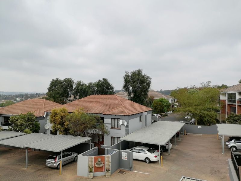 An elevated view of the apartment complex grounds, featuring covered parking bays and established landscaping.