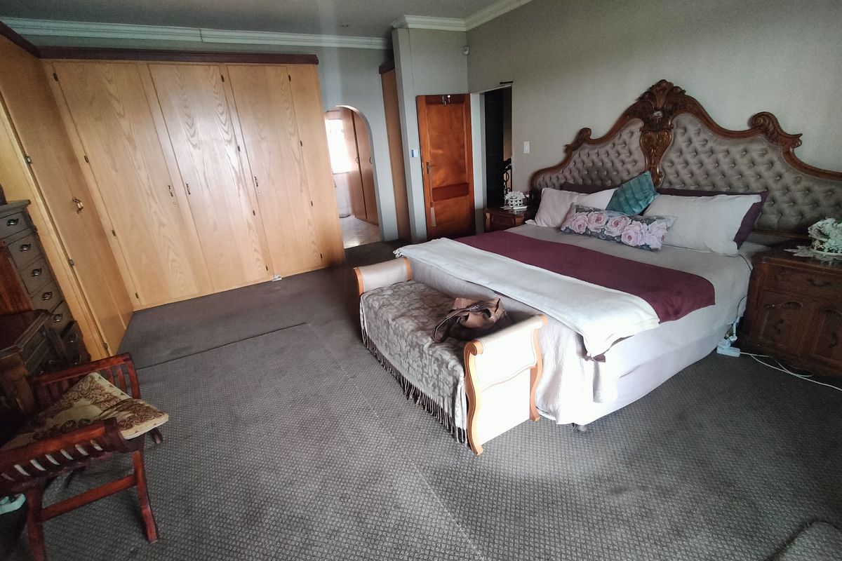 Spacious bedroom featuring extensive built-in wooden cabinetry, recessed ceiling lighting, and an arched doorway leading to an adjoining space.