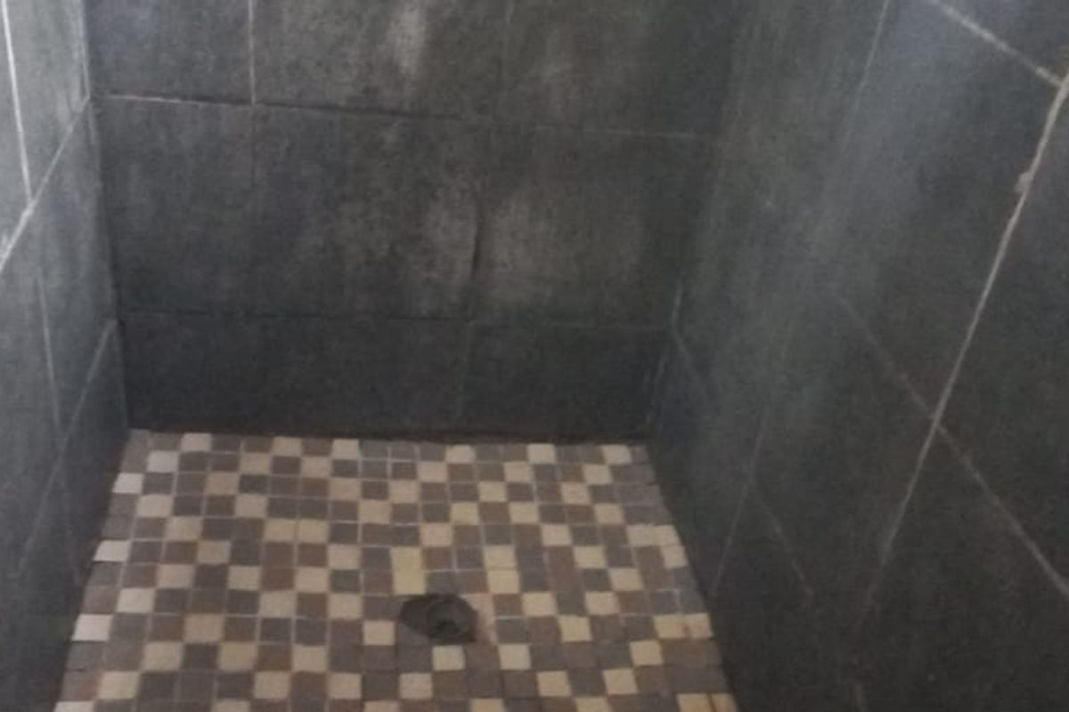 A shower enclosure featuring dark wall tiles and a mosaic tiled floor.