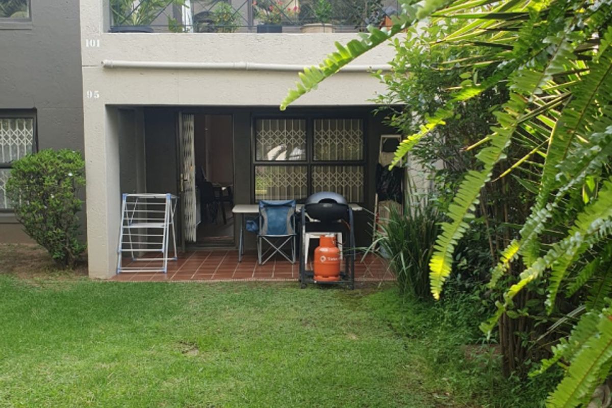 Ground floor patio area with tiled flooring, leading out to a private garden space, featuring a balcony above.