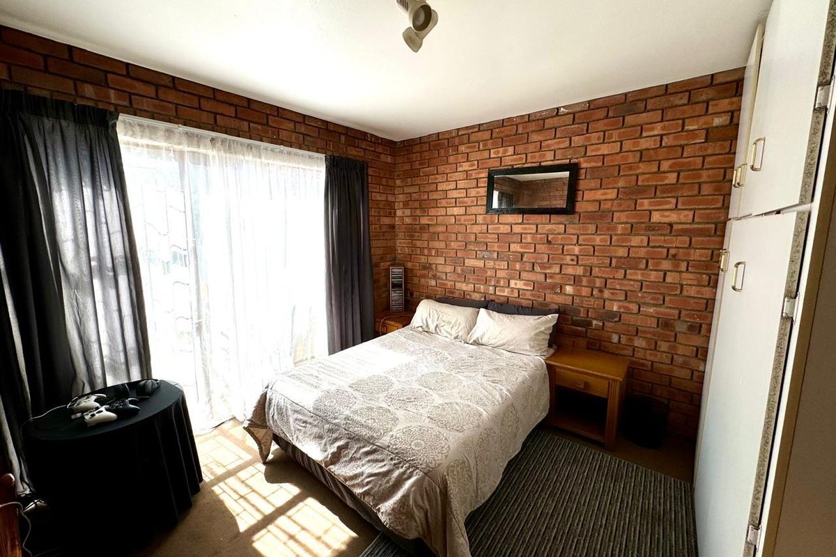 A bedroom featuring exposed brick feature walls, built-in cabinetry, and sliding glass door access to the exterior.
