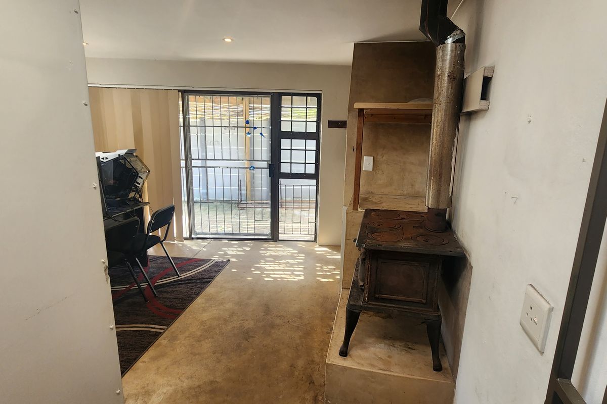 Living area featuring a cast iron fireplace with flue, concrete flooring, and a sliding door leading to an outdoor space with security gate.