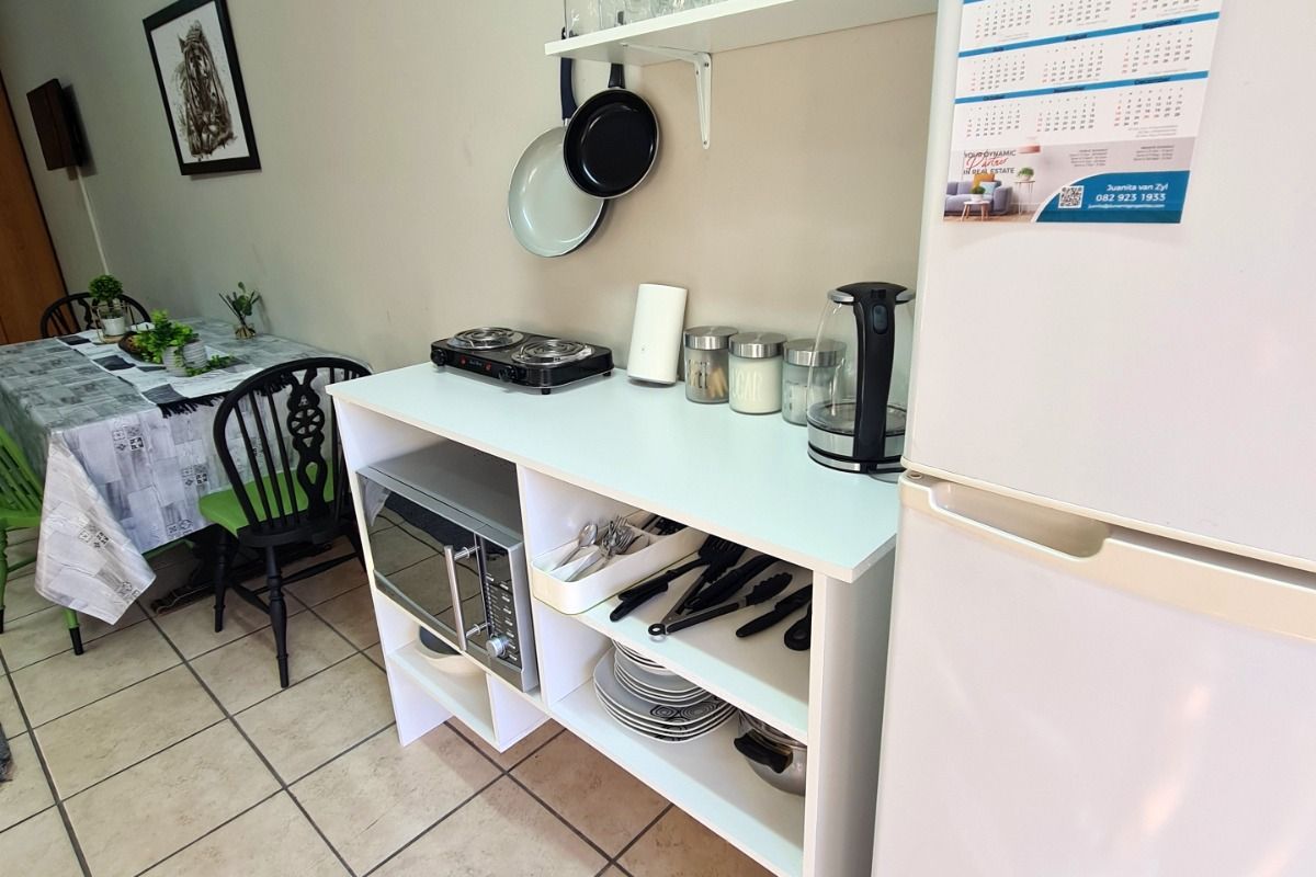 A compact kitchen area featuring tiled flooring, open shelving, and a built-in microwave, providing functional prep space within the open-plan layout.