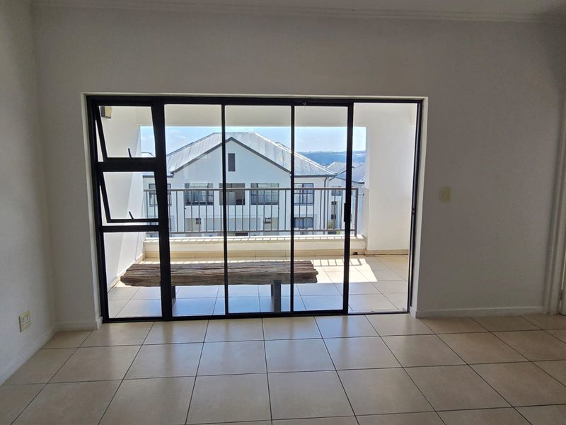 Bright and spacious living area featuring neutral tiled flooring and large sliding glass doors that open onto a private balcony.